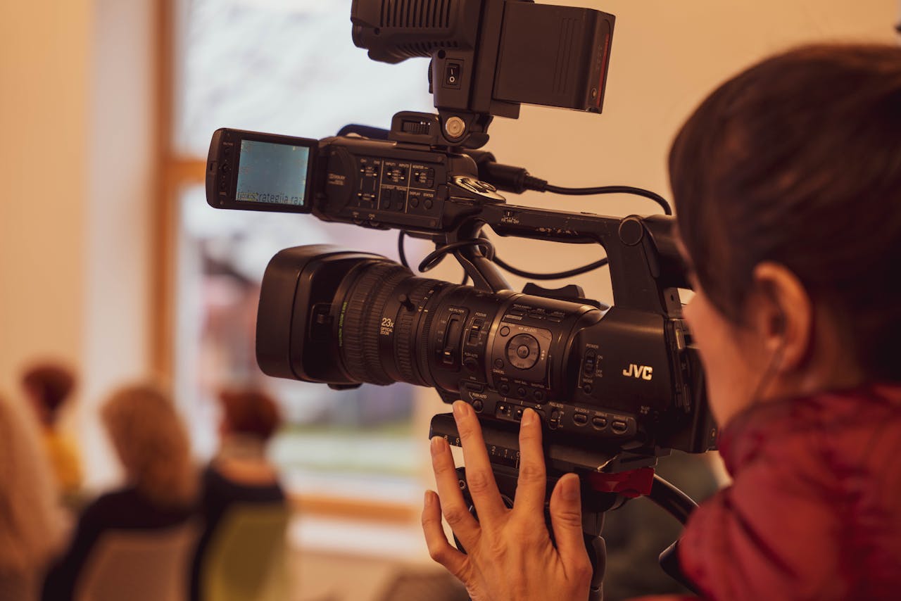 A skilled videographer using a video camera to capture footage indoors.
